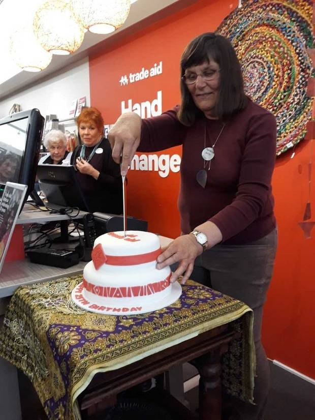 Trade Aid Rotorua's longest-serving volunteer Heather Doelman cutting the birthday cake.